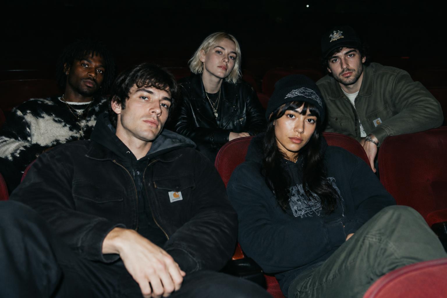 A group of independent artists sitting together in a dark theater